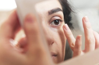 aynaya bakarak kendini makyaj yapıyor kız