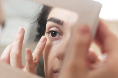 aynaya bakarak kendini makyaj yapıyor kız