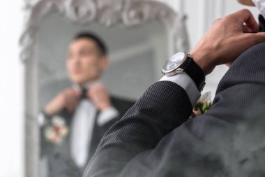 adam aynaya bakar ve papyonu düzeltir