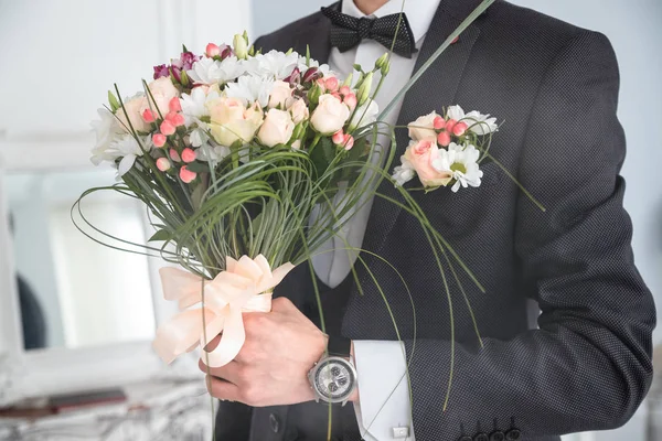 An elegant young man in a black suit and with a clock on his hand — Stock Photo, Image