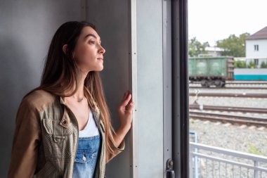 Genç bir kız tren kapısından dışarı bakıyor. kız tatile gidiyor