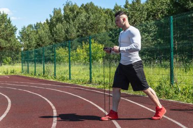 bir ip ile stadyumda atletik adam. Sağlıklı yaşam tarzı. Sokakta spor aktiviteleri
