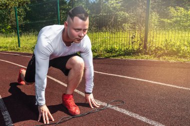 Genç kaslı sporcu stadyumdaki koşu bandının başında..