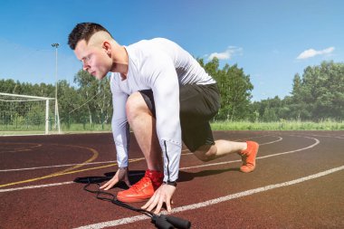 Genç kaslı sporcu stadyumdaki koşu bandının başında.