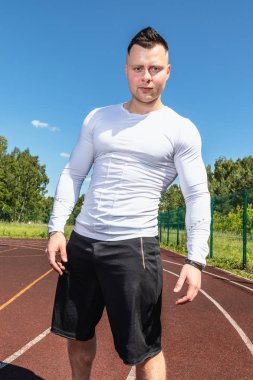 fitness, spor, egzersiz ve yaşam tarzı kavramı - atlet spor stadyumunda duruyor ve kameraya bakar.