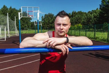 Spor stadyumundaki genç çalıştırıcı yatay bara yaslandı ve kameraya baktı.