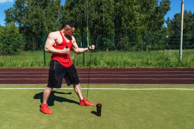 Siyah şort ve elinde bir ip ile kırmızı bir t-shirt Bodybuilder