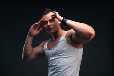 Beyaz tişörtlü güçlü genç adam parmaklarını şakağına dayıyor. Düşünce ve motivasyonun gücü