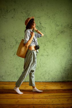 Kot ceketli, şapkalı, kameralı ve çantalı bir turist. Mutlu duygular