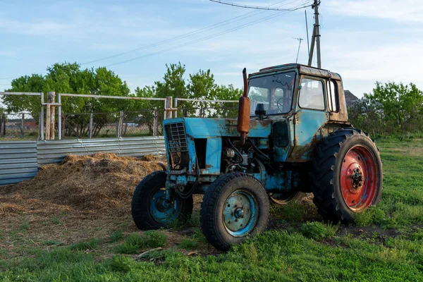 Abandoned old tractor in the village. Blue tractor with red wheel