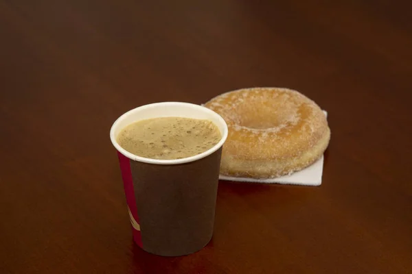 在棕色木桌背景上拿掉咖啡的甜甜圈 — 图库照片