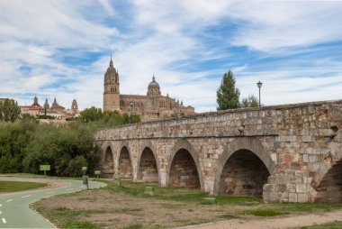 Roman bridge over the river Tormes and in the background the cathedrals of Salamanca clipart