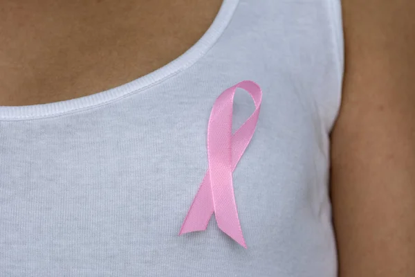 在女性胸部关闭粉红色丝带支持乳腺癌事业 — 图库照片