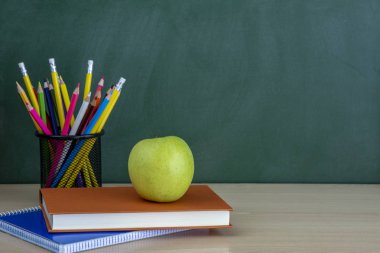 Tablo ve yeşil elma yazı tahtası ile kitap kopya alanı ile arka plan olarak kalem.