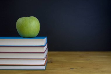 Kitaplar ve ahşap masa üzerinde elma yazı tahtası