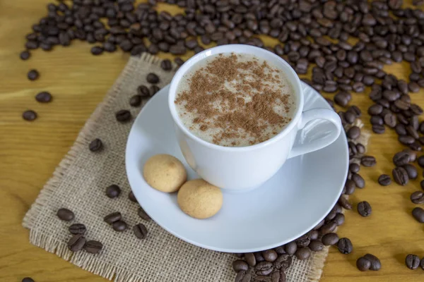 Heißer Kaffee mit Zimt und gerösteten Kaffeebohnen auf Holzrücken — Stockfoto