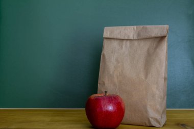 Okul yemeği. Kahverengi kağıt torba ve ahşap Resepsiyon üstüne kırmızı elma 