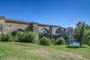 Roman bridge over the river Mino as it passes through the city of Ourense  clipart