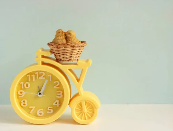 Reloj despertador amarillo con un pájaro sentado en un nido sobre un fondo claro —  Fotos de Stock