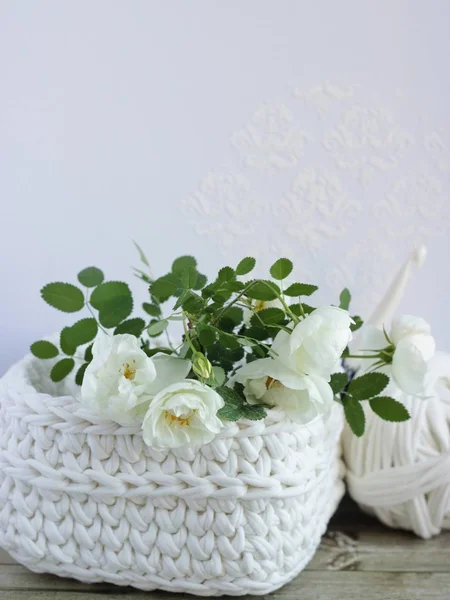 Gros plan crochet panier blanc avec branche d'arbuste blanc rose, une boule de fil blanc et un crochet sur table en bois. Fond blanc. Décoration artisanale, artisanat et arts, activité de loisir . — Photo