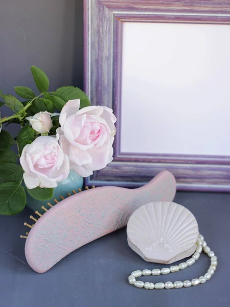 Belle rose tendre, brosse à cheveux, miroir de poche et bijoux sur la coiffeuse gris foncé. Cadre en lilas de bois rustique avec place blanche pour le texte. Peut être utilisé comme une carte — Photo