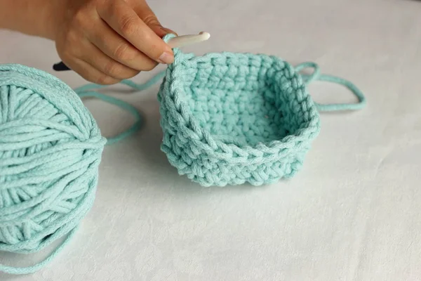 Tricot et crochet à main concept. Femmes tricoter à la main panier turquoise avec un grand crochet de la corde. Fond blanc. Vue supérieure avec espace de copie . — Photo