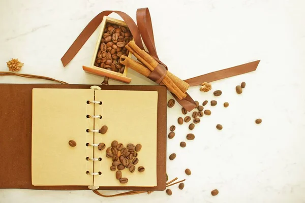 Coffee flat lay.Blank page old leather notepad for coffee recipes, cinnamon sticks and coffee beanes. Mock up empty notepad pages on white backdrop.Can be used for coffee menu.Top view with copy space
