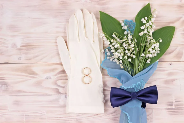 Bouquet de fleurs lis de la vallée en serviette turquoise, gants femme de mariage blanc et noeud papillon bleu sur table rustique légère.Belle carte de voeux de mariage, vue sur le dessus, espace pour le texte, pose plate. — Photo