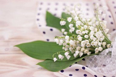 Bulanık çiçek arkaplanı. Açık yeşil masa üzerinde ipek ve dantel kumaşlı vadi çiçekleri bulanık. Gelin buketli güzel bir düğün kartı..