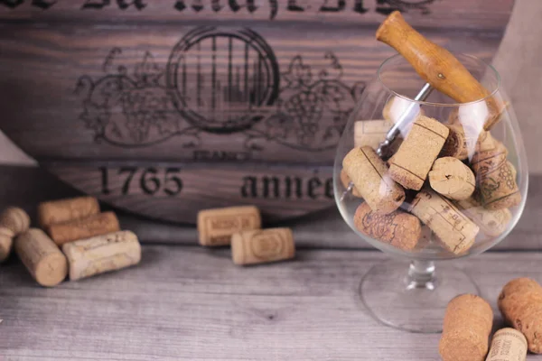 Korkenzieher und Korken in einem Weinglas aus nächster Nähe. Wein-Accessoires auf dunklen Scheunenbrettern und altem antiken Fasshintergrund.Weinbau und Weinbereitungskonzept. — Stockfoto