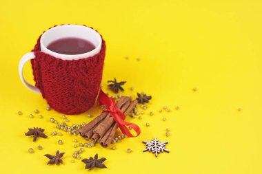 Sarı arka planda yün çantalı sıcak şarap. Güzel örgü kırmızı çantalı, baharatlı ve altın parıltılı. Kopya spazmlı bayram arkaplanı. Yeni yıl tebrik kartı..