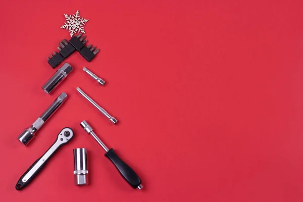 Kırmızı arka planda yaratıcı noel ağacı, anahtarlardan yapılmış, xmas arka planında tamir için araç gereçlerden yapılmış. Endüstriyel tebrik kartı ve yeni yıl konsepti..