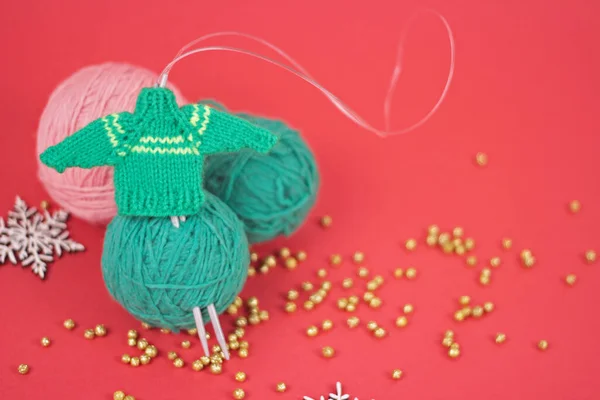 Aiguilles à tricoter et boules de fil vert et rose en fond rouge.Carte de voeux du Nouvel An des Fêtes. — Photo