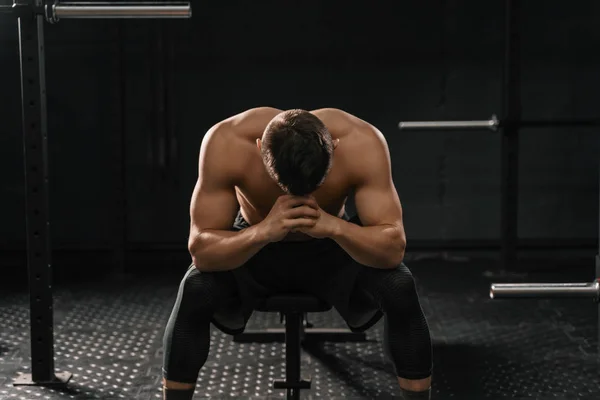 Üstesinden gelmek için arıza acı spor salonu bankta oturan güçlü sportif adam. Demotivation spor kavramı.