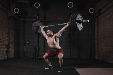 Genç crossfit atlet spor salonunda ağır halter ek yük kaldırma. Fonksiyonel eğitim yapan yakışıklı erkek. Powerlifting pratik.