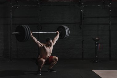 Genç atlet crossfit spor salonunda halter ek yük kaldırma. Kaslı adam pratik powerlifting.