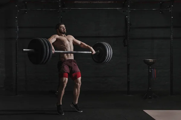 Kaslı adam crossfit spor salonunda bir halter kaldırma.