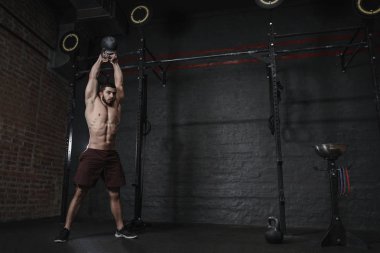 Crossfit spor salonunda Kettlebells salıncak egzersiz yaparak atlet. Fonksiyonel eğitim egzersiz pratik yapan yakışıklı erkek. Kopya alanı.