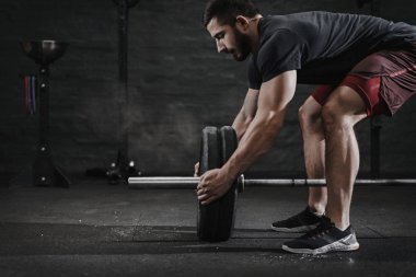 Genç crossfit atlet spor salonunda ağırlık kaldırma için halter hazırlanıyor. Magnesia koruma toz bulutu. Fonksiyonel eğitim yapan yakışıklı erkek. Powerlifting pratik. Egzersiz Egzersizler.