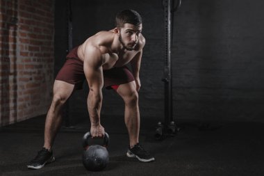 Crossfit atlet spor salonunda bir kettlebell ile egzersiz. Fonksiyonel eğitim egzersiz pratik yapan kaslı erkek