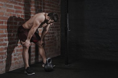 Atlet krizi aşmak için acı salonunda duvara yaslanmış. Demotivation spor kavram. Stres ve yorgunluk sporda. CrossFit kettlebell eğitim. Kopya alanı.