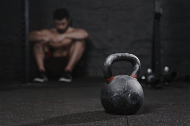 Üstesinden gelmek için sportif adam arıza acı spor salonunda oturuyor. Demotivation spor kavram. Stres ve yorgunluk sporda. CrossFit kettlebell eğitim.