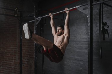 Crossfit atlet yatay çubuk üzerinde ABS egzersizleri yapıyor. Jimnastik salonunda pratik.