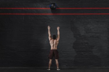 CrossFit atlet spor salonunda topu atar. Fonksiyonel eğitim yapan yakışıklı erkek. Egzersiz Egzersizler. Tuğla duvar kopya alanı. Metin için yer.