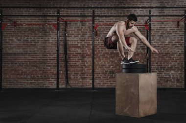 Genç fit atlet spor salonunda atlama kutusu yapıyor çapraz. Fonksiyonel eğitim pratik adam. Metin için yer