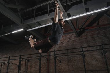 Jimnastik yüzük pull-up spor yapıyor üzerinde sallanan genç crossfit atlet. Egzersiz Egzersizler
