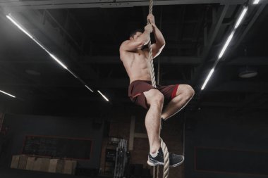 Crossfit atlet spor salonunda bir halat tırmanma. Fonksiyonel eğitim yapan yakışıklı erkek. Egzersiz Egzersizler