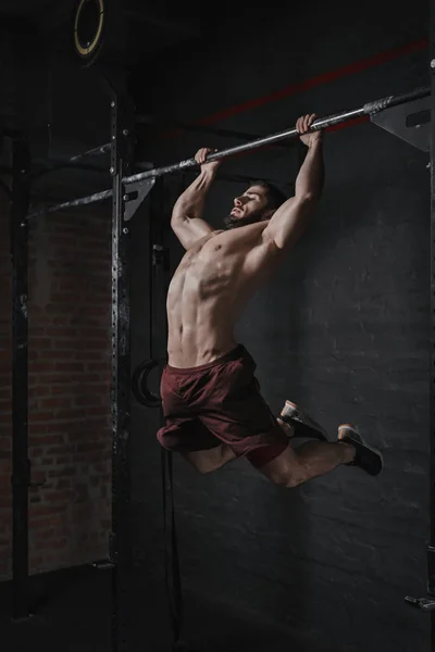Genç crossfit atlet pull-up spor yapıyor. Fonksiyonel eğitim yapan yakışıklı erkek. Jimnastik pratik.