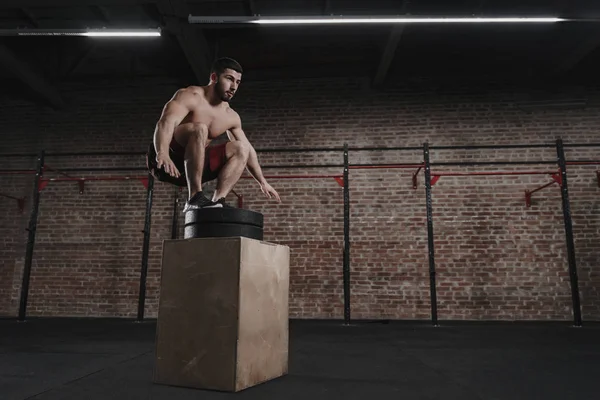 Young athlete doing box jump at crossfit gym. Workout exercises. Copy space