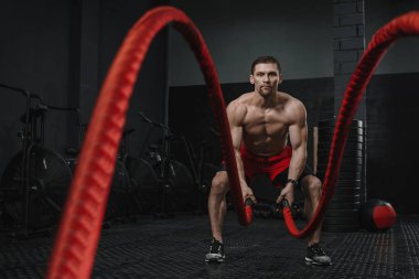 Kaslı adam savaşında crossfit spor salonunda egzersiz ipleri